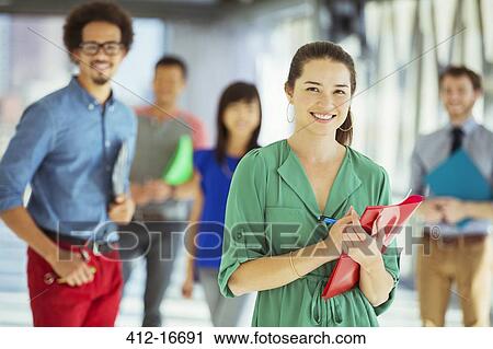 Portrait of creative businesswoman with folder and co-workers in corridor View Large Photo Image Stock Image - Portrait of creative businesswoman with folder and co-workers in corridor. Fotosearch