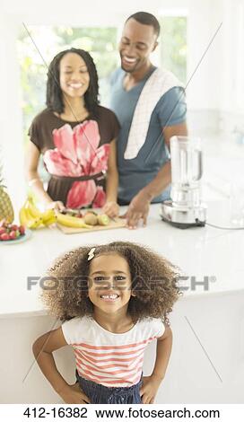 Portrait of enthusiastic girl in kitchen with parents in background View Large Photo Image Stock Image - Portrait of enthusiastic girl in kitchen with parents in background. Fotosearch