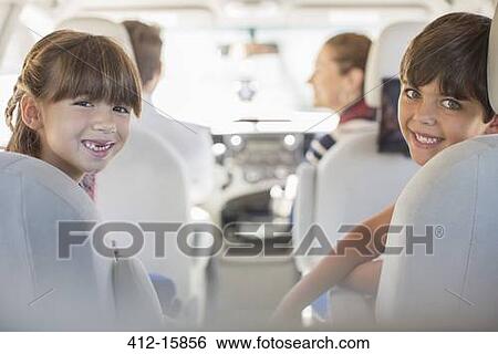 Stock Photograph - Portrait of happy brother and sister in back seat of car. Fotosearch
