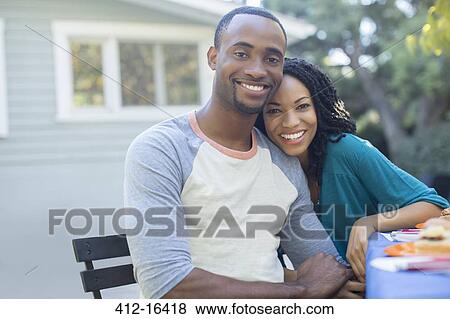 Stock Photo - Portrait of happy couple holding hands at patio table. Fotosearch