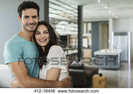 Portrait of happy couple hugging at home View Large Photo Image Stock Photograph - Portrait of happy couple hugging at home. Fotosearch