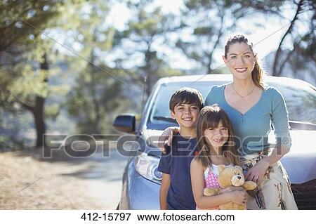 Stock Photo - Portrait of happy family leaning on car. Fotosearch