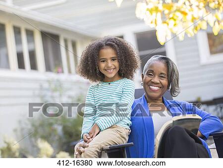 Stock Image - Portrait of happy grandmother and granddaughter on patio. Fotosearch