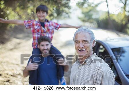 Stock Photograph - Portrait of happy multi-generation men outside car. Fotosearch