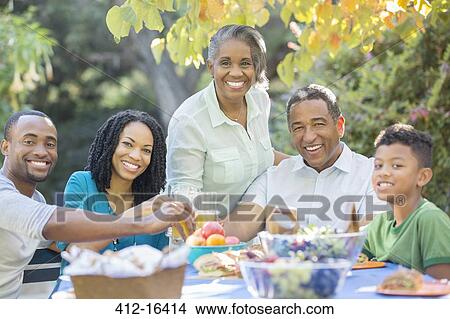 Portrait of happy multi-generation family eating lunch at patio table View Large Photo Image Picture - Portrait of happy multi-generation family eating lunch at patio table. Fotosearch