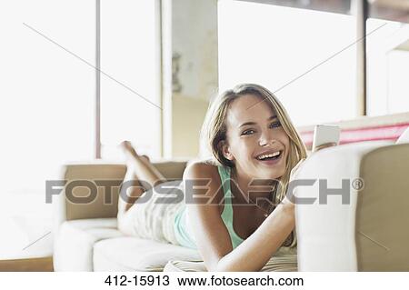 Portrait of happy woman texting with cell phone on sofa View Large Photo Image Stock Image - Portrait of happy woman texting with cell phone on sofa. Fotosearch