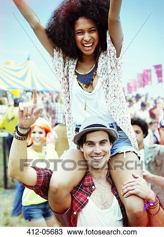 Portrait of man carrying enthusiastic woman on shoulders at music festival View Large Photo Image Stock Image - Portrait of man carrying enthusiastic woman on shoulders at music festival. Fotosearch
