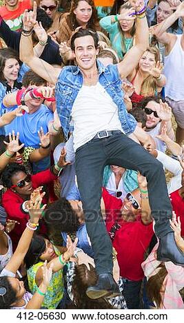 Stock Image - Portrait of man crowd surfing at music festival. Fotosearch