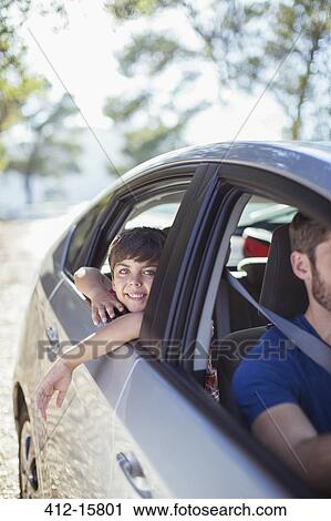 Stock Image - Portrait of smiling boy leaning out car window. Fotosearch