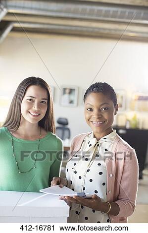 Portrait of smiling businesswomen with paperwork in office View Large Photo Image Stock Image - Portrait of smiling businesswomen with paperwork in office. Fotosearch