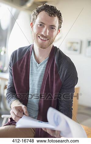 Stock Photo - Portrait of smiling casual businessman with paperwork in office. Fotosearch