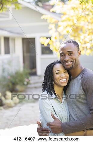 Portrait of smiling couple hugging outside house View Large Photo Image Stock Photo - Portrait of smiling couple hugging outside house. Fotosearch