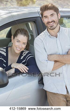 Portrait of smiling couple inside and outside car View Large Photo Image Stock Photo - Portrait of smiling couple inside and outside car. Fotosearch