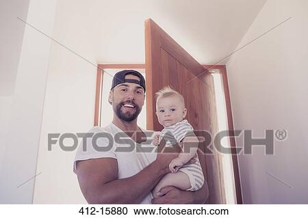 Portrait of smiling father holding baby son in doorway View Large Photo Image Stock Image - Portrait of smiling father holding baby son in doorway. Fotosearch