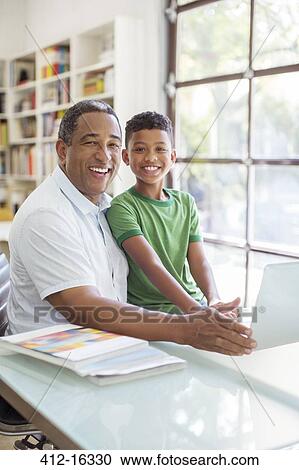 Stock Image - Portrait of smiling grandfather and grandson using laptop. Fotosearch