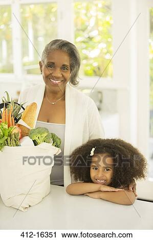Portrait of smiling grandmother and granddaughter with groceries in kitchen View Large Photo Image Stock Image - Portrait of smiling grandmother and granddaughter with groceries in kitchen. Fotosearch