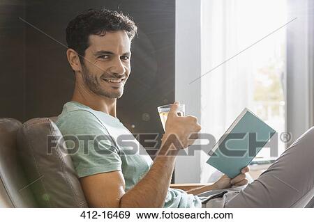 Portrait of smiling man drinking tea and reading book View Large Photo Image Stock Photo - Portrait of smiling man drinking tea and reading book. Fotosearch