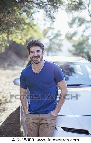 Stock Image - Portrait of smiling man leaning on car. Fotosearch