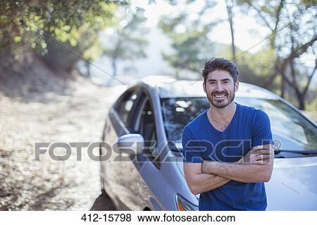 Stock Photo - Portrait of smiling man leaning on car. Fotosearch