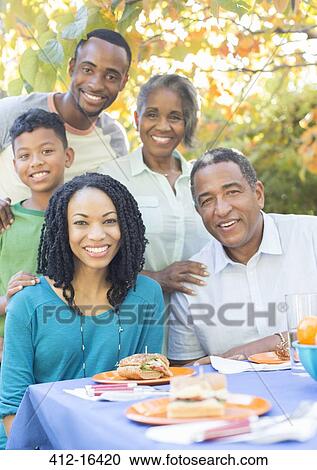 Portrait of smiling multi-generation family eating lunch at patio table View Large Photo Image Stock Image - Portrait of smiling multi-generation family eating lunch at patio table. Fotosearch