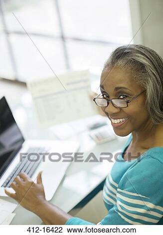 Portrait of smiling senior woman paying bills at laptop View Large Photo Image Stock Image - Portrait of smiling senior woman paying bills at laptop. Fotosearch