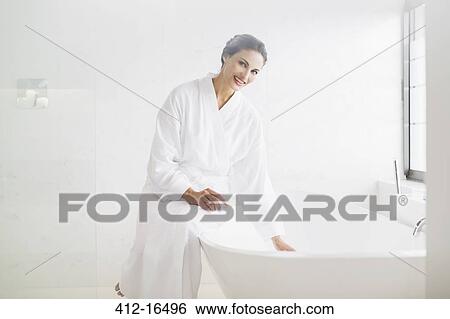 Stock Photograph - Portrait of smiling woman in bathrobe preparing bath. Fotosearch
