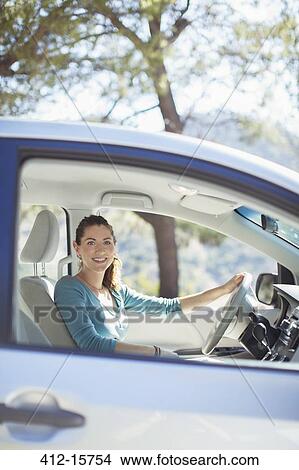 Picture - Portrait of smiling woman inside car. Fotosearch