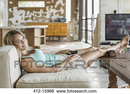 Portrait of smiling woman laying on sofa with remote control View Large Photo Image Stock Photo - Portrait of smiling woman laying on sofa with remote control. Fotosearch