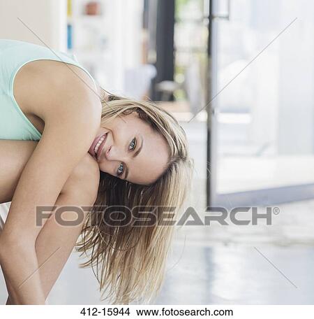 Picture - Portrait of smiling woman leaning over legs. Fotosearch