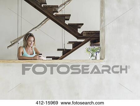 Portrait of smiling woman texting on cell phone at table View Large Photo Image Stock Photo - Portrait of smiling woman texting on cell phone at table. Fotosearch