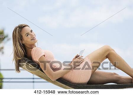Portrait of smiling woman using digital tablet on lounge chair View Large Photo Image Stock Photo - Portrait of smiling woman using digital tablet on lounge chair. Fotosearch