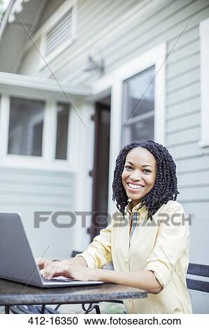 Portrait of smiling woman using laptop at patio table View Large Photo Image Stock Image - Portrait of smiling woman using laptop at patio table. Fotosearch