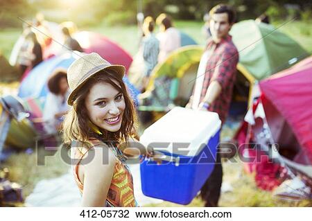 Portrait of woman helping man carry cooler outside tents at music festival View Large Photo Image Stock Image - Portrait of woman helping man carry cooler outside tents at music festival. Fotosearch