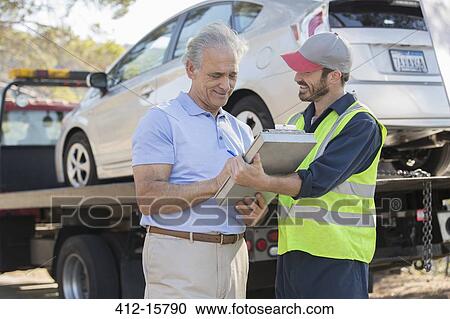 Stock Image - Roadside mechanic and man with paperwork. Fotosearch