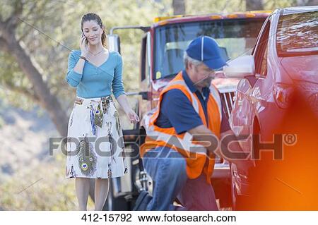 Roadside mechanic fixing flat tire for woman on cell phone View Large Photo Image Stock Image - Roadside mechanic fixing flat tire for woman on cell phone. Fotosearch