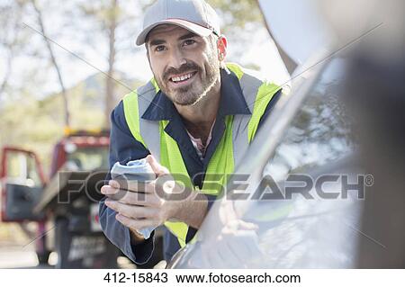 Stock Image - Roadside mechanic leaning on car. Fotosearch