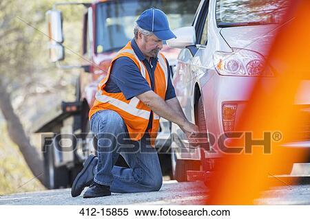 Roadside mechanic repairing flat tire View Large Photo Image Stock Photography - Roadside mechanic repairing flat tire. Fotosearch