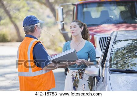Stock Image - Roadside mechanic talking with woman. Fotosearch