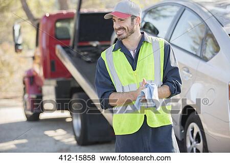 Roadside mechanic wiping hands with cloth next to tow truck View Large Photo Image Stock Photo - Roadside mechanic wiping hands with cloth next to tow truck. Fotosearch