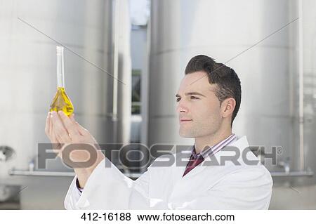 Scientist examining liquid in beaker next to silage storage towers View Large Photo Image Stock Photo - Scientist examining liquid in beaker next to silage storage towers. Fotosearch
