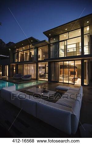 Stock Photo - Sectional sofa at poolside of luxury house at night. Fotosearch