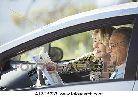 Stock Image - Senior couple looking at map inside car. Fotosearch