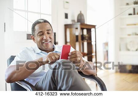 Senior man text messaging with cell phone in living room View Large Photo Image Stock Image - Senior man text messaging with cell phone in living room. Fotosearch