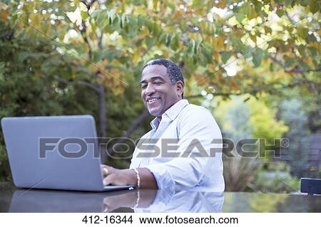 Senior man using laptop at patio table View Large Photo Image Picture - Senior man using laptop at patio table. Fotosearch
