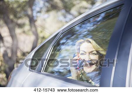 Senior woman talking on cell phone in car View Large Photo Image Stock Image - Senior woman talking on cell phone in car. Fotosearch