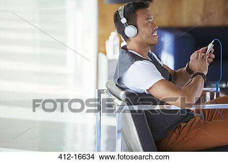 Smiling businessman listening to music on mp3 player with headphones View Large Photo Image Picture - Smiling businessman listening to music on mp3 player with headphones. Fotosearch