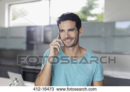 Smiling man talking on cell phone in kitchen View Large Photo Image Stock Image - Smiling man talking on cell phone in kitchen. Fotosearch