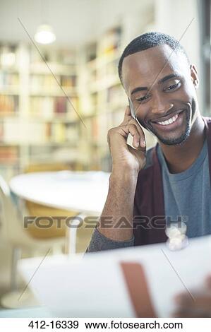 Stock Photo - Smiling man with paperwork talking on cell phone. Fotosearch
