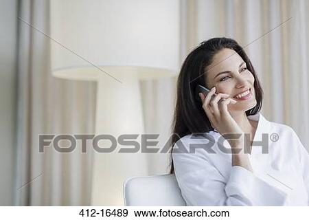 Smiling woman in bathrobe talking on cell phone at home View Large Photo Image Stock Photo - Smiling woman in bathrobe talking on cell phone at home. Fotosearch