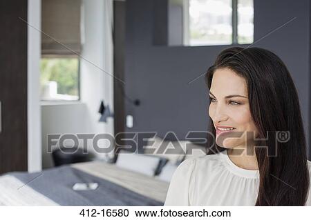 Stock Image - Smiling woman in bedroom. Fotosearch
